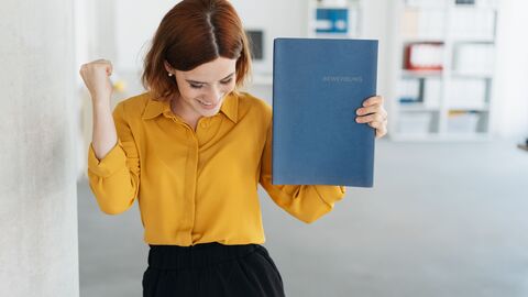 Junge Frau mit Mappe in der Hand freut sich