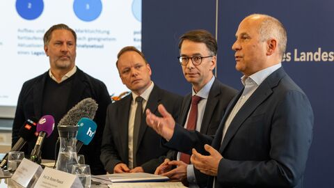 Vier Personen stehen nebeneinander und vor ihnen stehen Mikrofone.